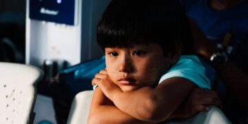 boy leaning on white chair
