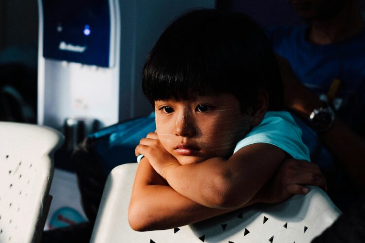 Boy leaning on white chair