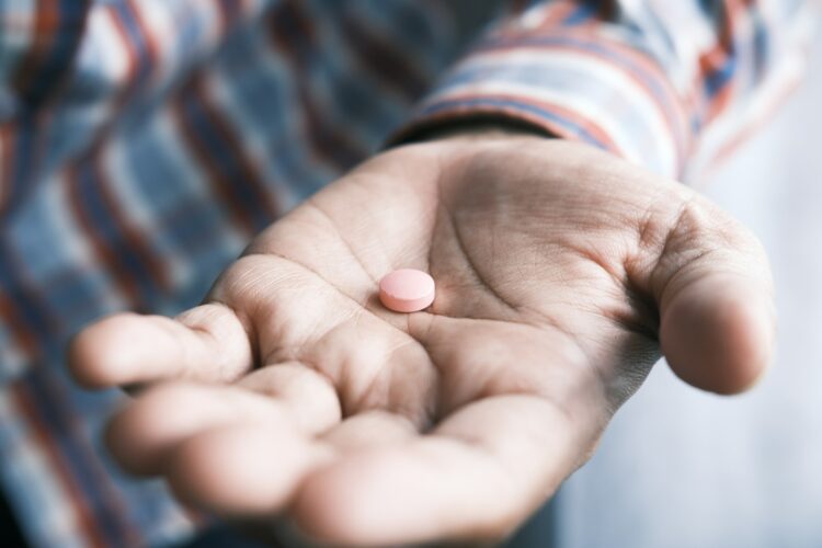 Person holding pink round medication pill