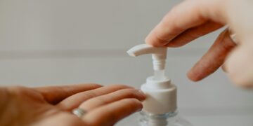 person holding white plastic pump bottle