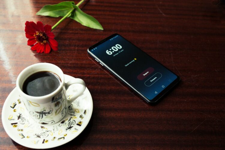 Smartphone near cup of coffee on table