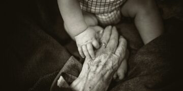 an older woman holding a baby's hand