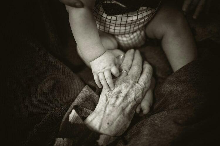 An older woman holding a baby's hand
