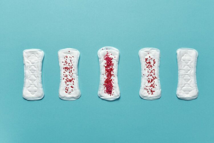 Various menstrual pads arranged on a blue background showcasing stages of use