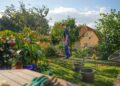 Man walks through a lush garden with a house