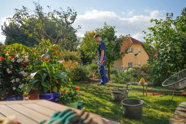 Man walks through a lush garden with a house