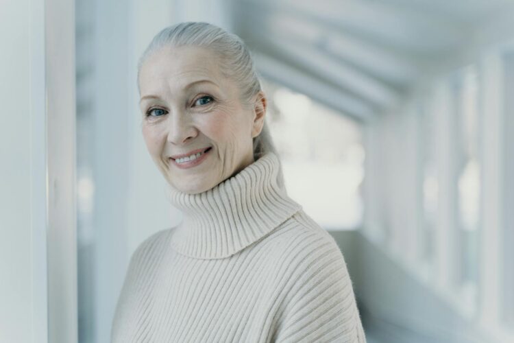 Elegant senior woman with grey hair smiling in a serene indoor setting