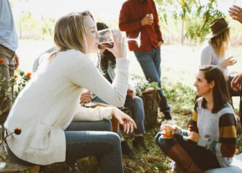 Woman sitting near people while drinking
