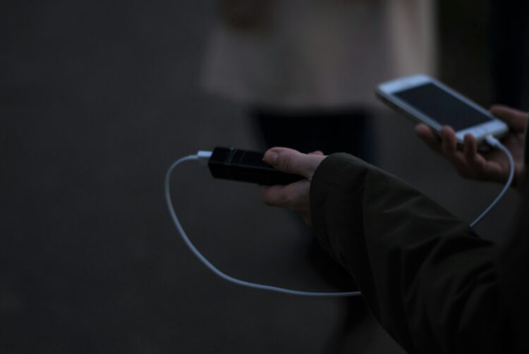 A person holding a cell phone and a charger