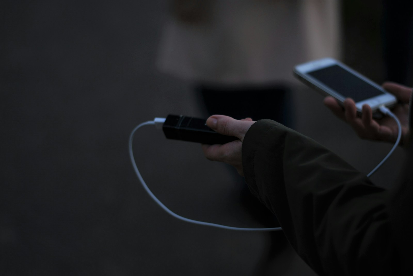 A person holding a cell phone and a charger