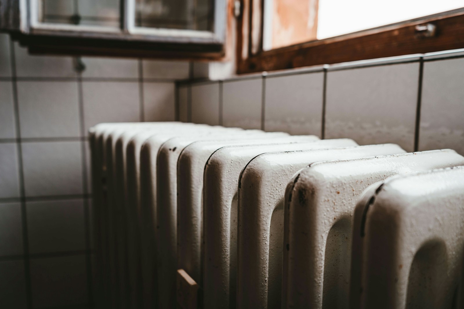 Photo by Julian Hochgesang - Info Vandaag White radiator heater beside brown wooden window