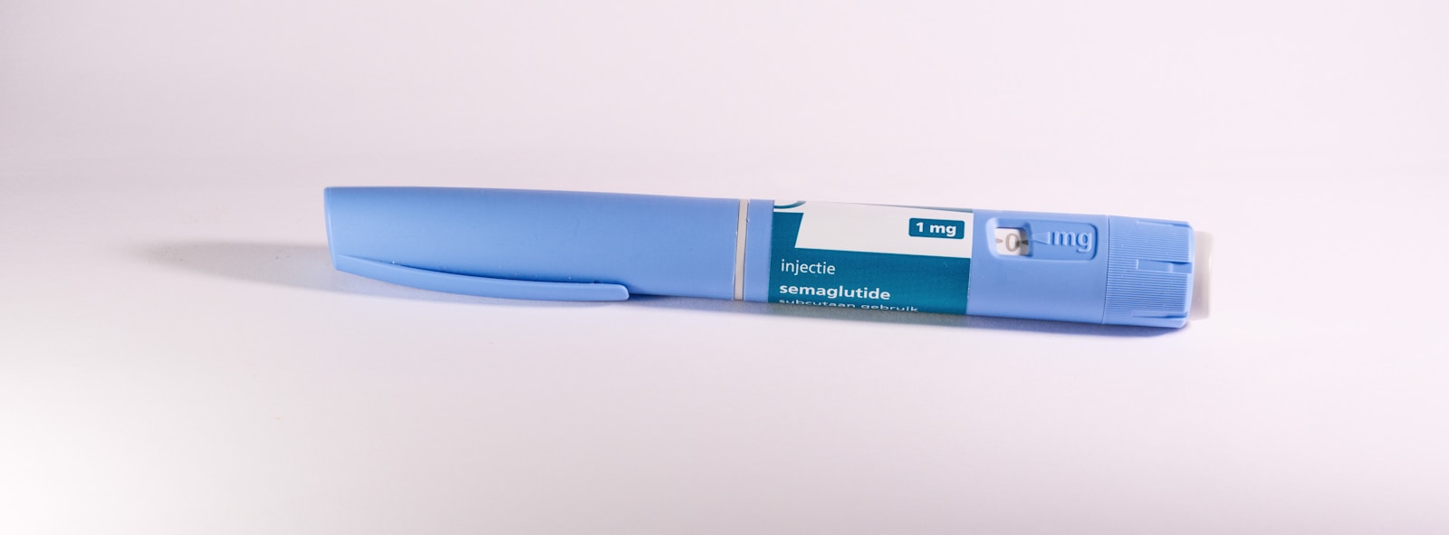 A blue insulin pen rests on a white surface