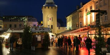 a crowd of people walking around a city at night