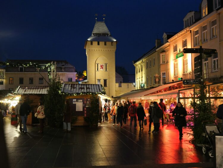 A crowd of people walking around a city at night