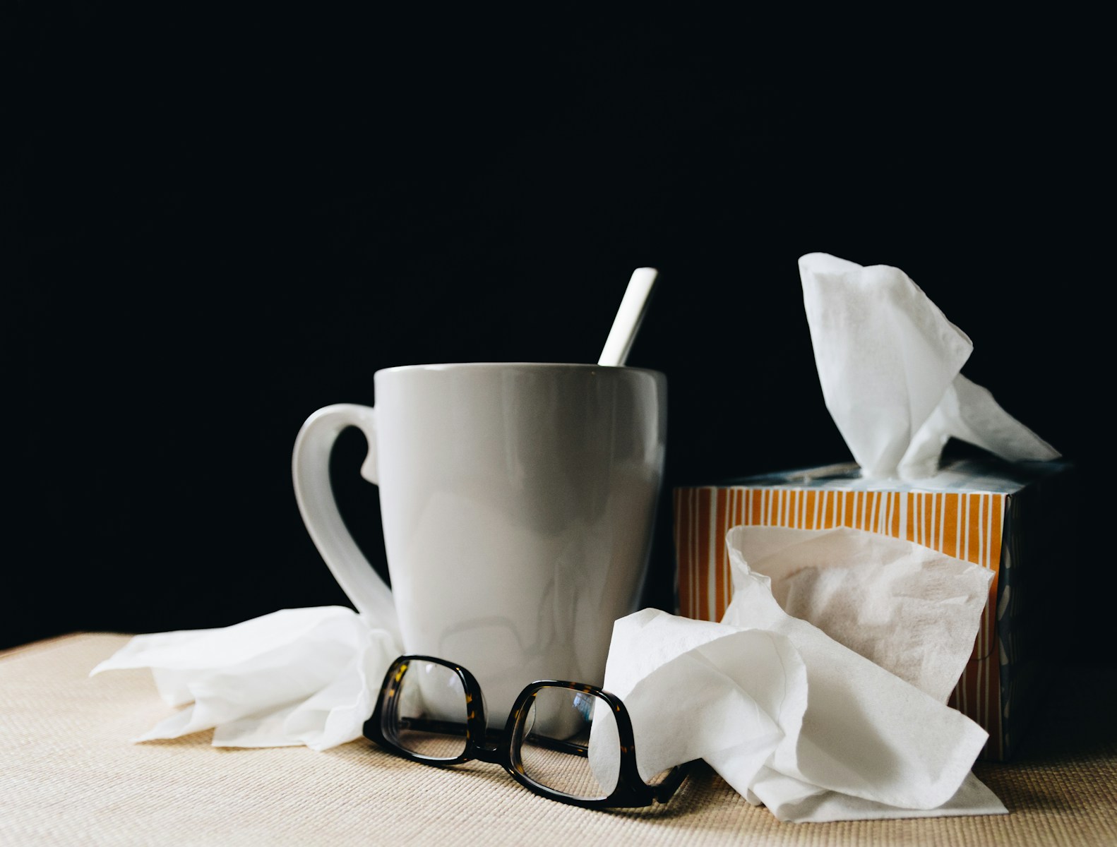 White ceramic mug on white table beside black eyeglasses