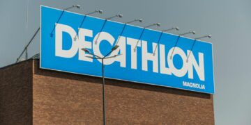 Close-up of a Decathlon store sign against a clear sky on a brick building.