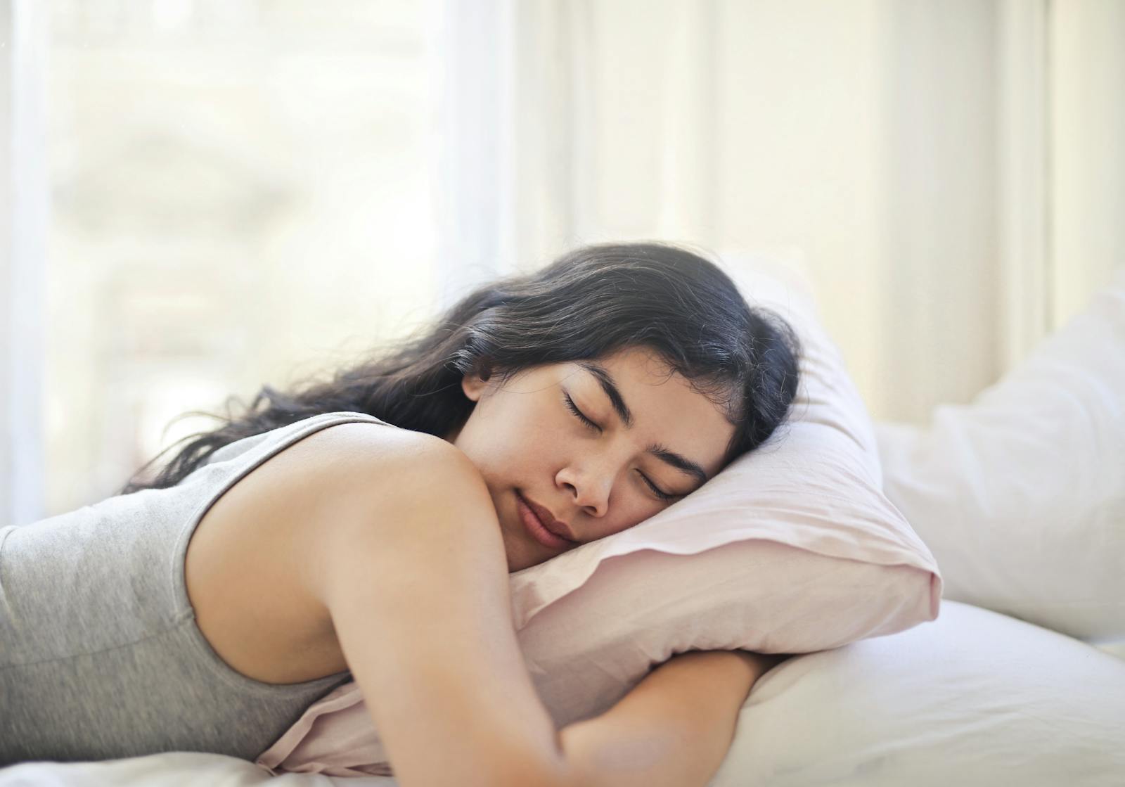 Serene woman resting on a comfortable bed with soft pillows and natural light