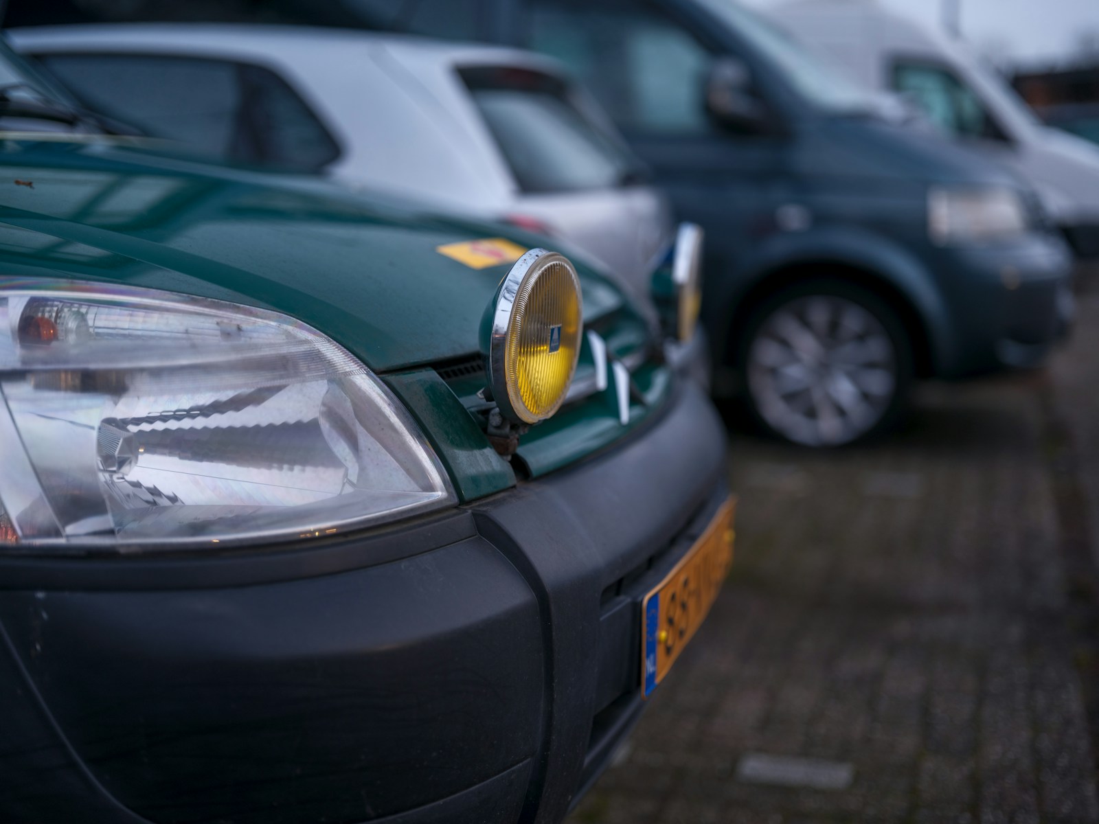 A parking meter sitting next to a row of parked cars