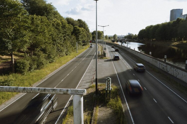 Cars drive on a highway next to a river