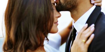 man kissing woman on her forehead