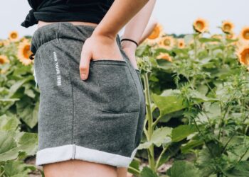 Woman standing on sunflower meadow holding pocket