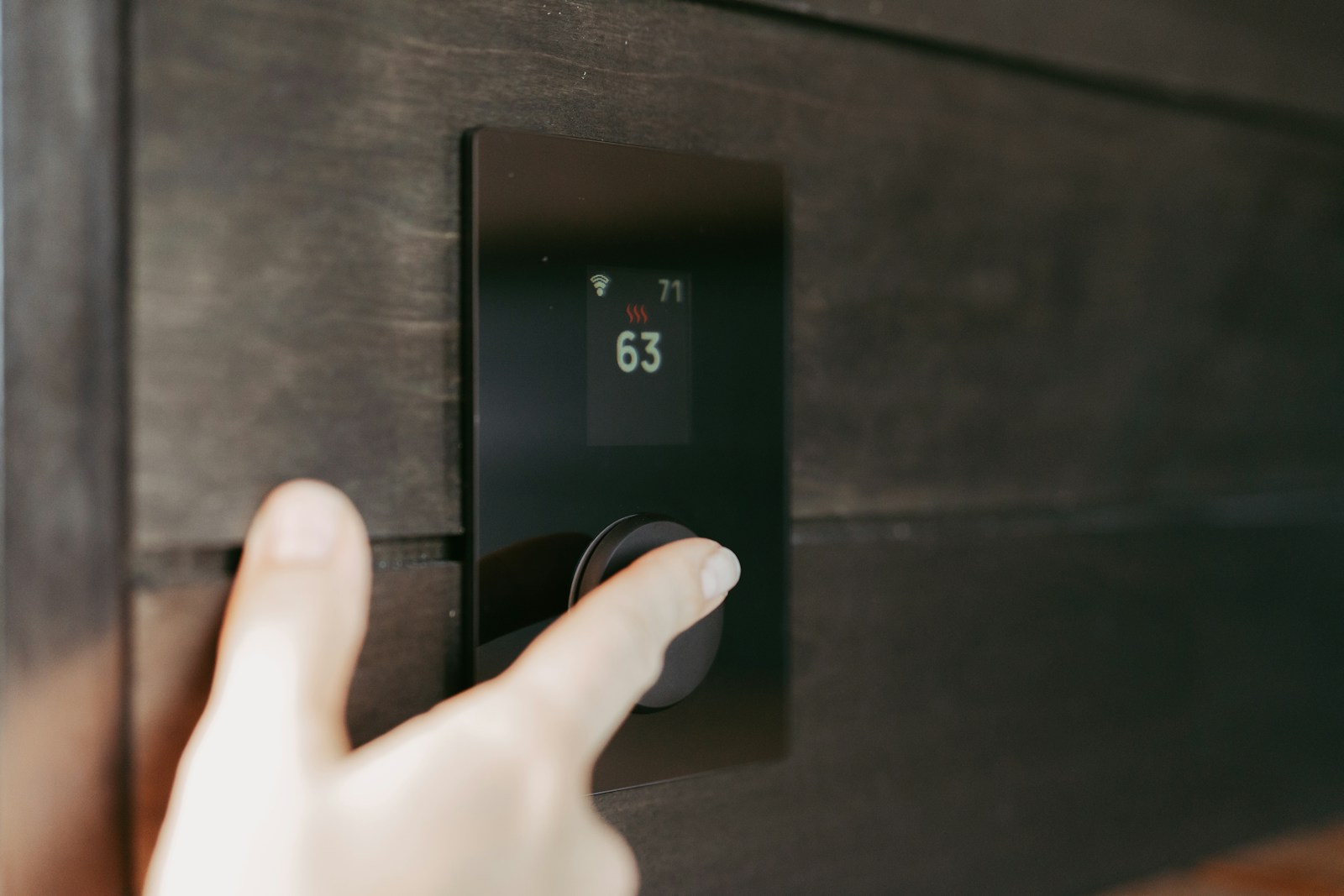 Hand adjusting a digital thermostat display