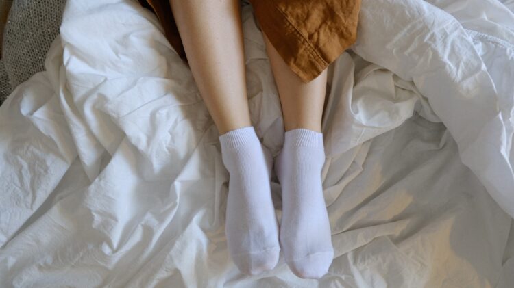Person wearing white socks on white textile