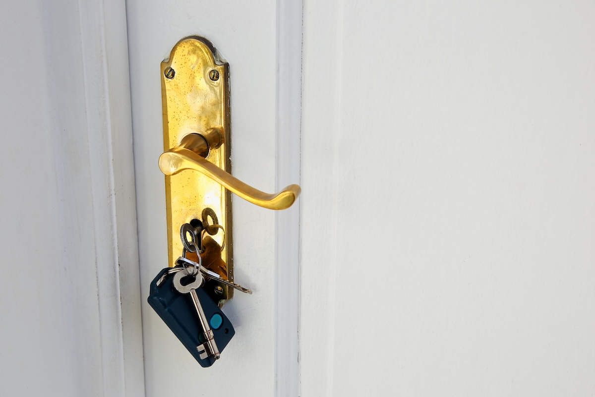 A golden doorknob with keys on a white door - Info Vandaag