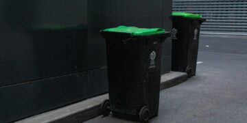 two black trash bins beside wall