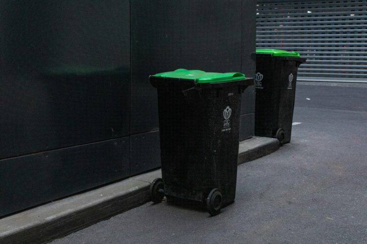 Two black trash bins beside wall