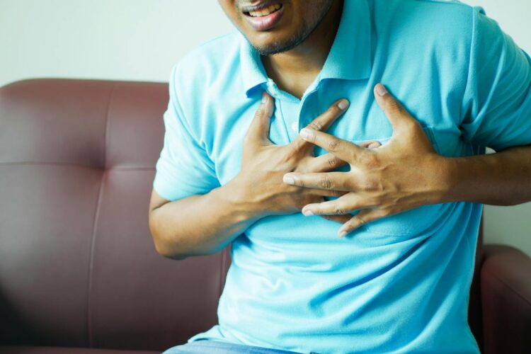 A close up image of a man clutching his chest indicating heart pain or discomfort