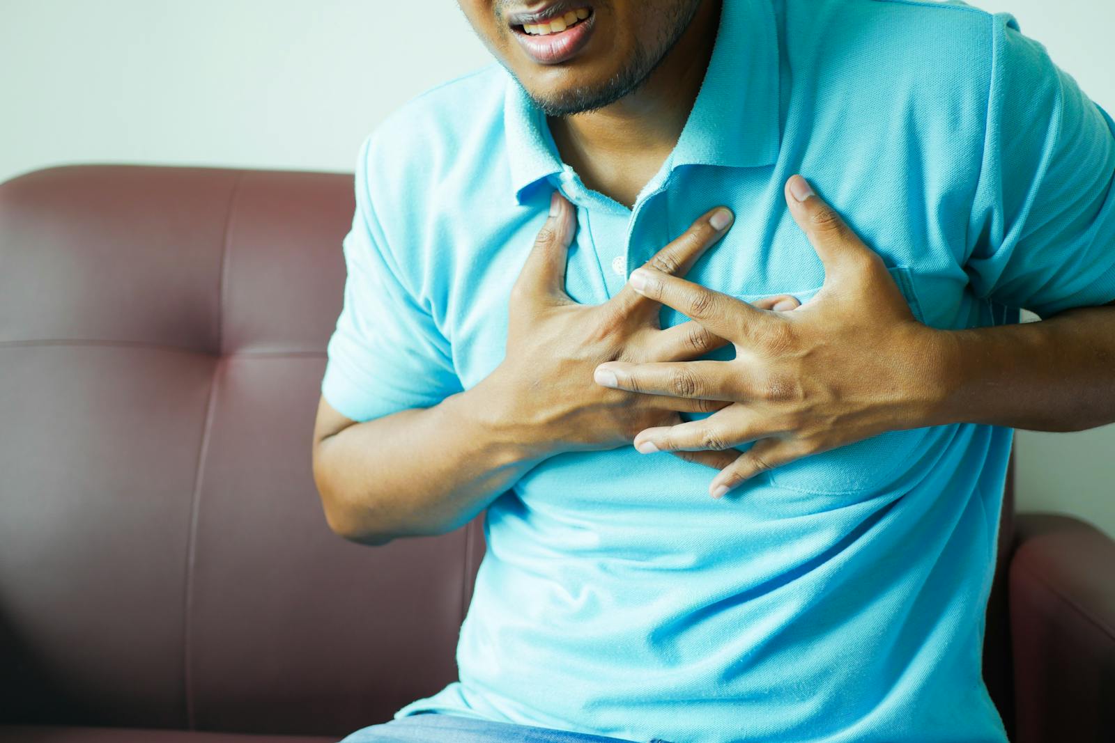 A close up image of a man clutching his chest indicating heart pain or discomfort