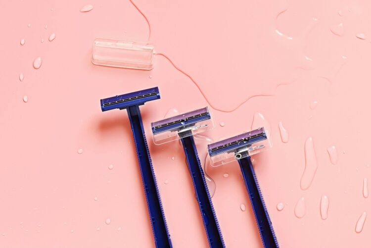 Three blue toothbrushes sitting on top of a pink surface