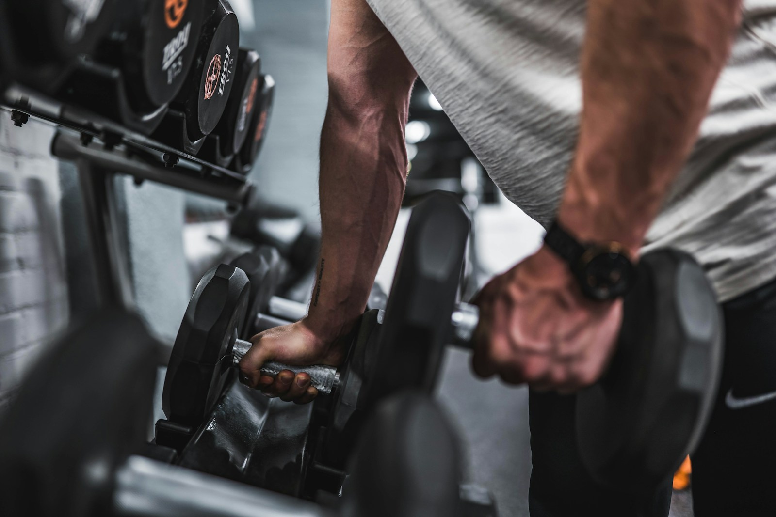 Person in gray shirt holding black dumbbell