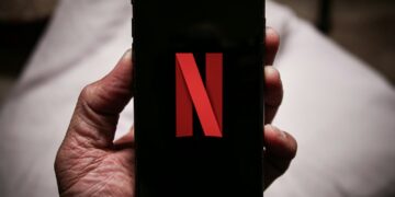 a person holding a cell phone with the letter n on it