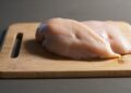 A piece of raw chicken on a cutting board