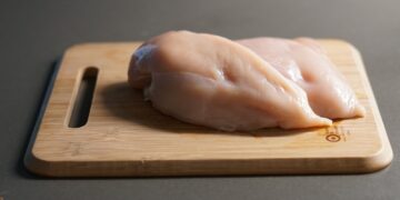 A piece of raw chicken on a cutting board