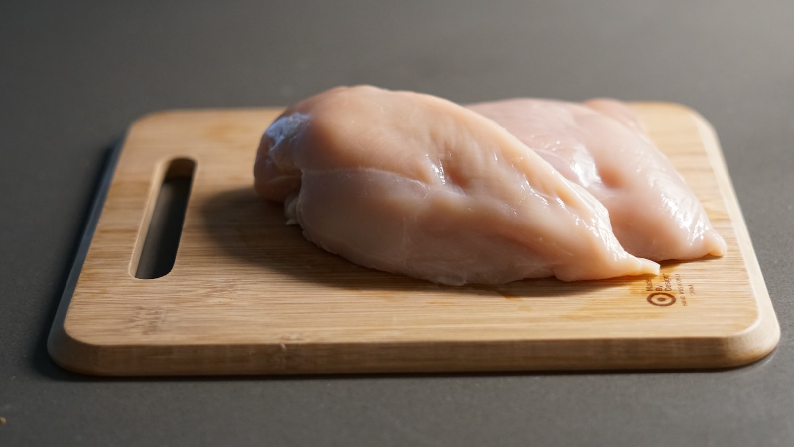 A piece of raw chicken on a cutting board