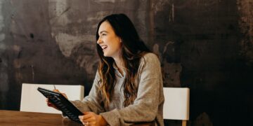 woman sitting around table holding tablet