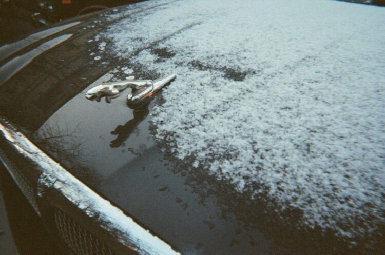 A car covered in snow next to a parking meter