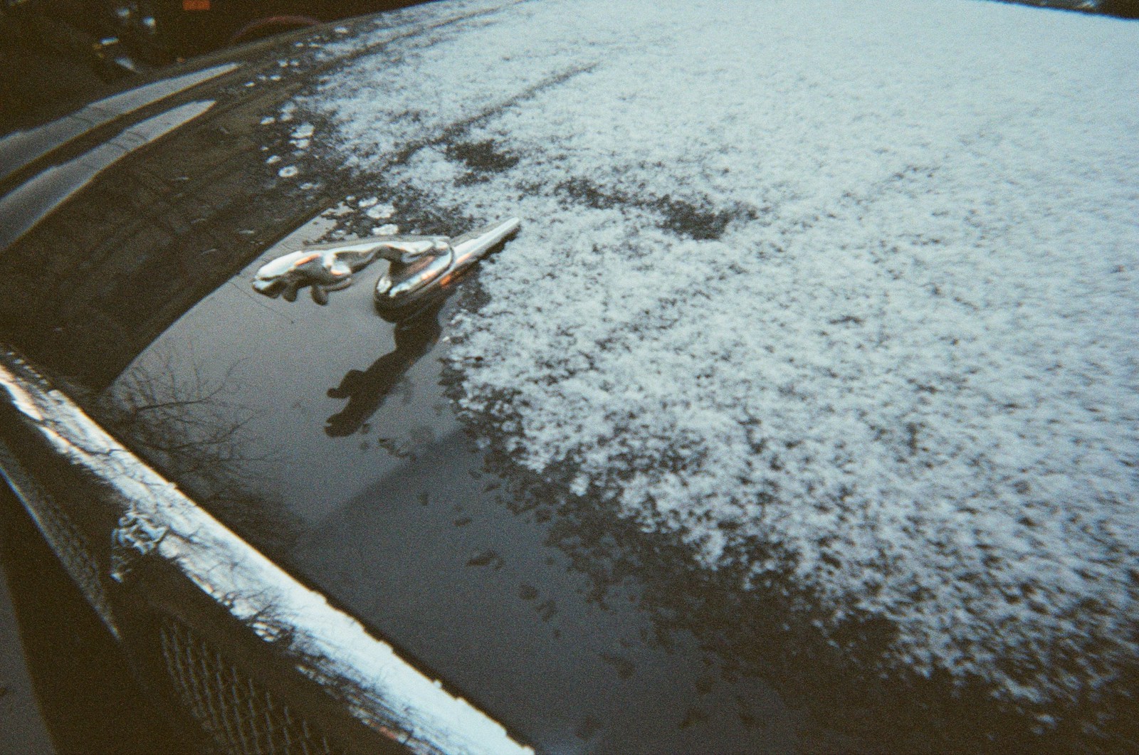 A car covered in snow next to a parking meter