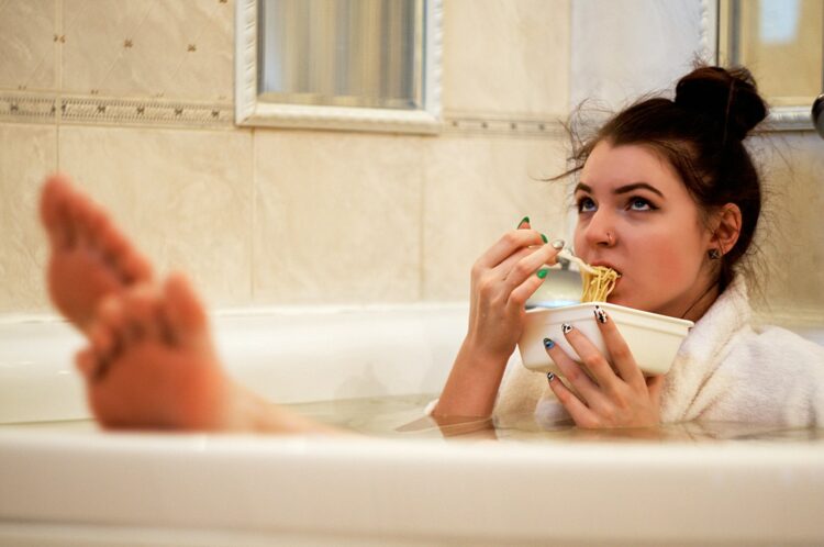 Girl in bathtub holding white ceramic mug
