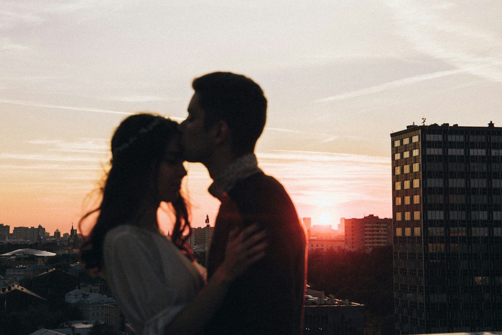A man and a woman kissing in front of a sunset