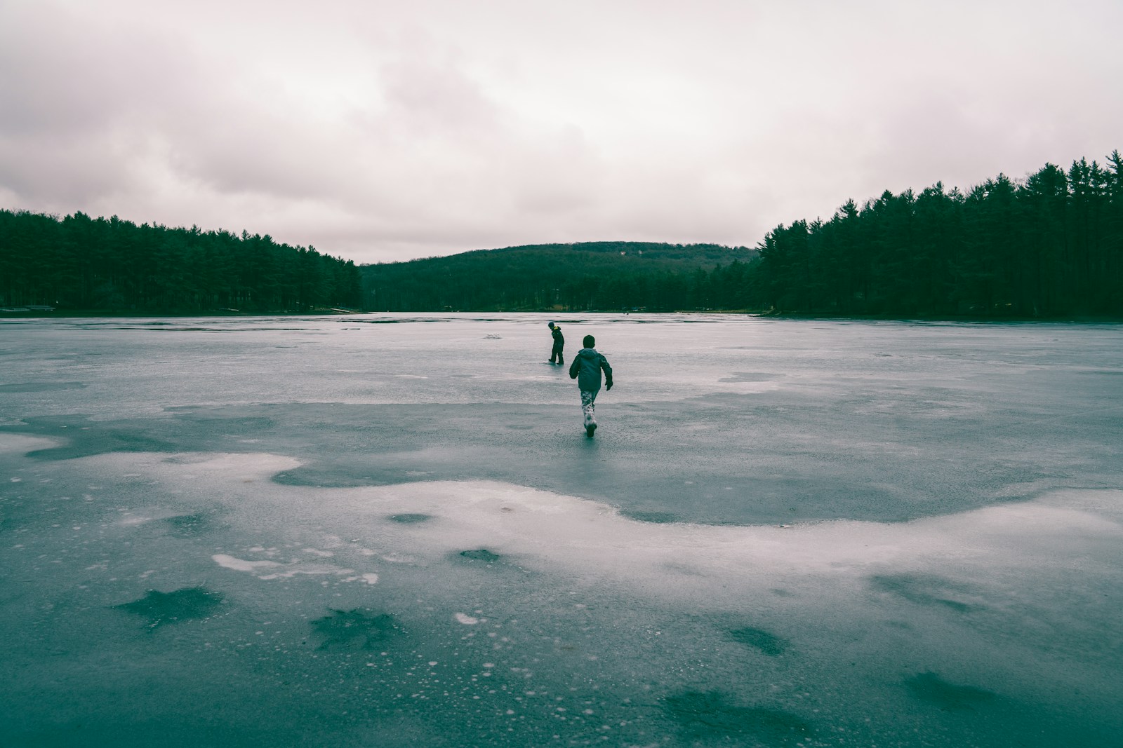 Photo by Michael Aleo - Info Vandaag Two people in middle of frozen body of water near trees