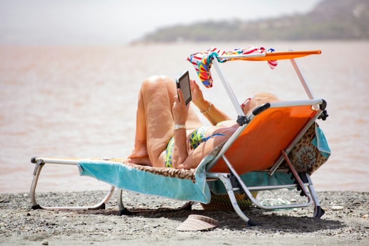 Woman in white bikini lying on blue and white surfboard on beach during daytime