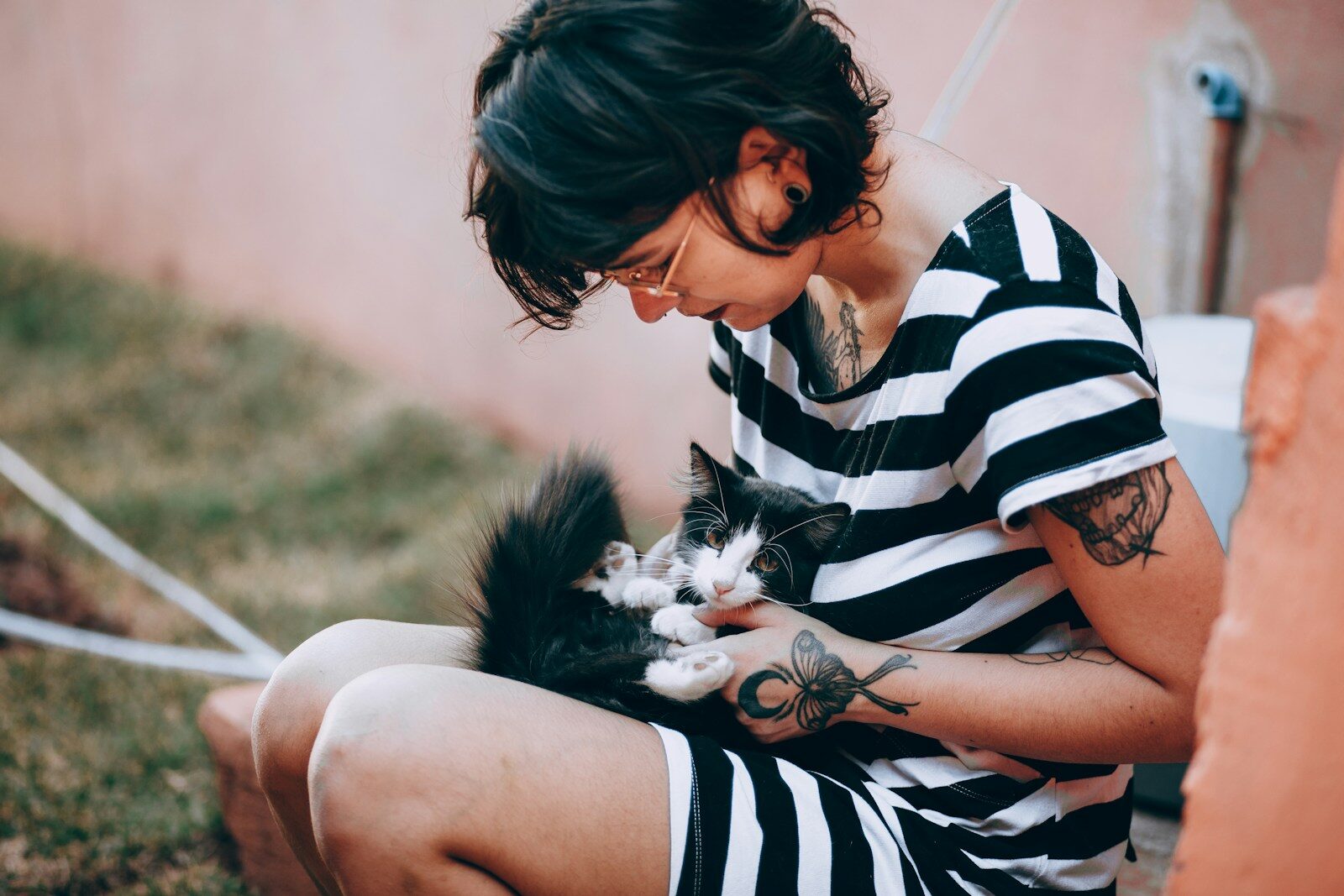 Woman in black and white stripe shirt holding black and white cat