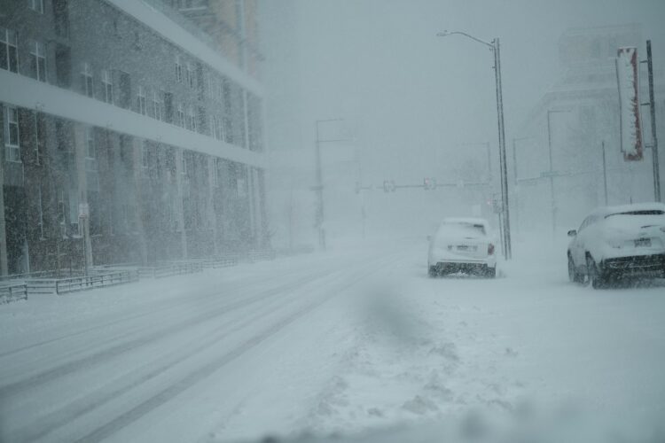 A couple of cars driving down a snow covered street