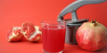 clear drinking glass with red liquid beside red apple fruit