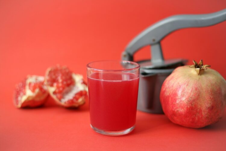 Clear drinking glass with red liquid beside red apple fruit