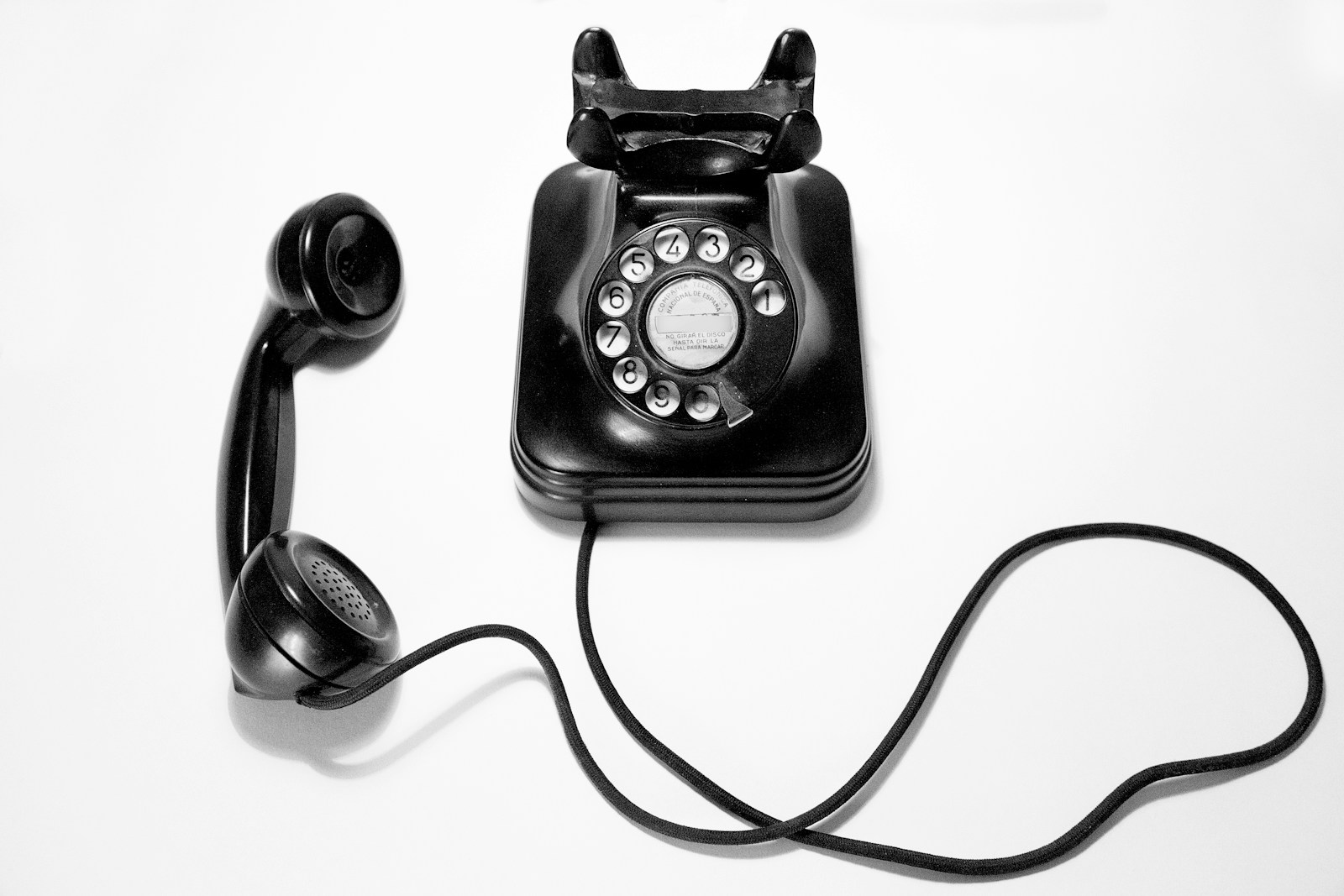 Black rotary dial phone on white surface